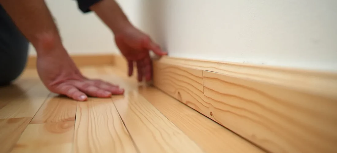 Installation d'un plinth bois contre un mur blanc